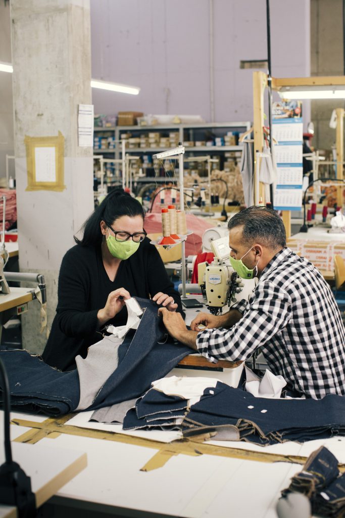 Sina Trinkwalder, Gründerin von Manomama bespricht mit einem ihrer Mitarbeiter die Herstellung von Jeans. 150 Frauen und Männer aus 25 Nationen arbeiten für Manomama. Anders als in Asien verdienen sie hier mehr als den Mindestlohn.