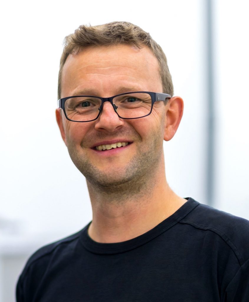 Porträtfoto von Daniel Tigges, Geschäftsführer des Kölner Eco-Instituts. Er trägt ein schwarzes T-Shirt, eine schwarze Brille.
